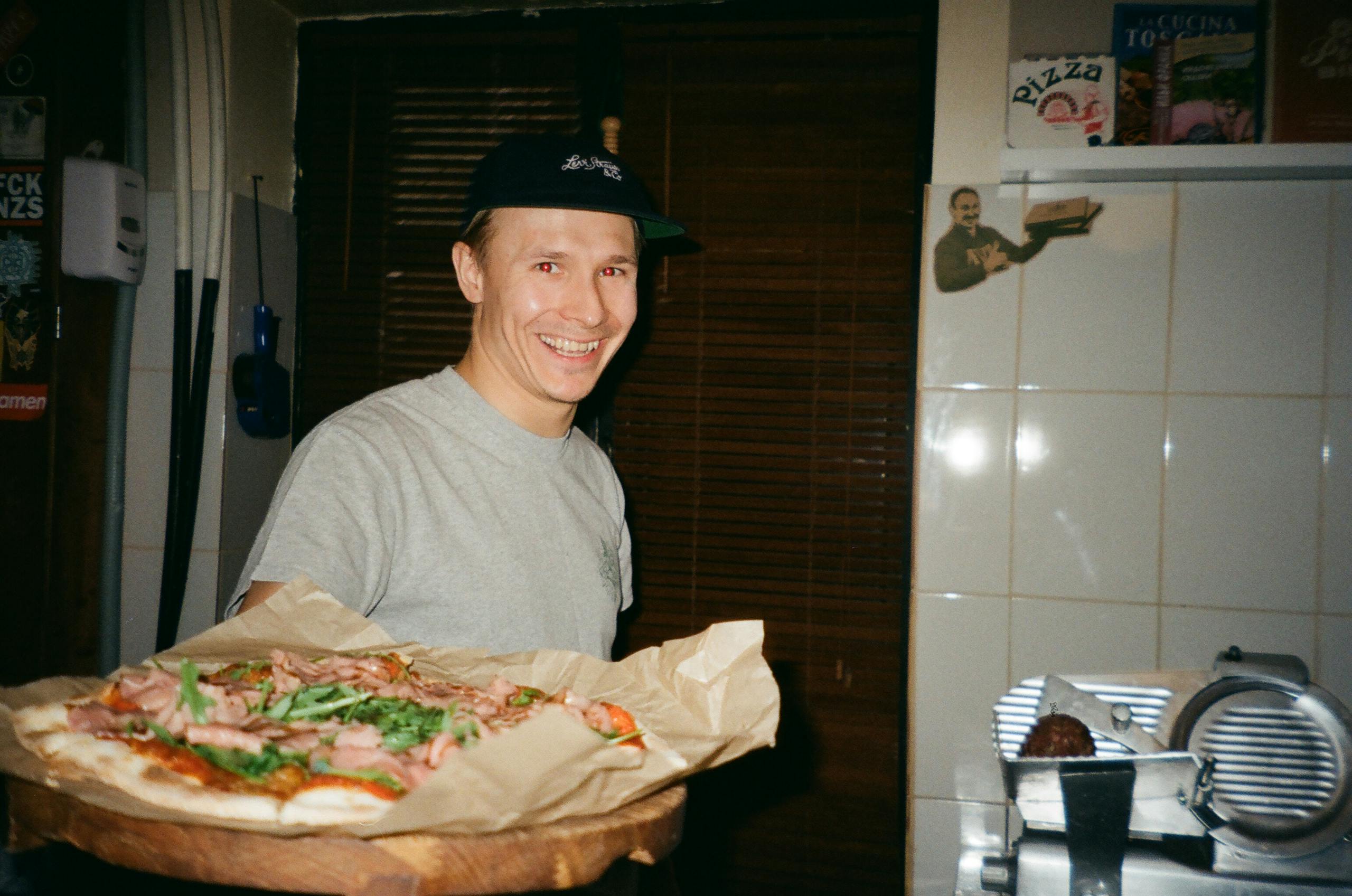 A cheerful chef presenting a delicious homemade pizza in a cozy kitchen setting.
