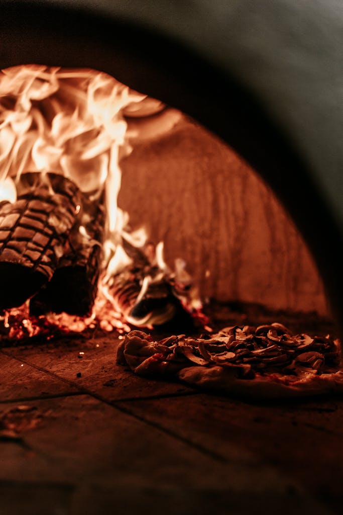 A delicious Italian pizza cooking in a traditional wood-fired oven with intense flames.